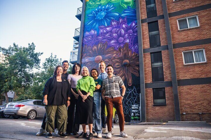 Kat Simmer posing in front of her brand new BUMP Mural "Pride in Bloom"