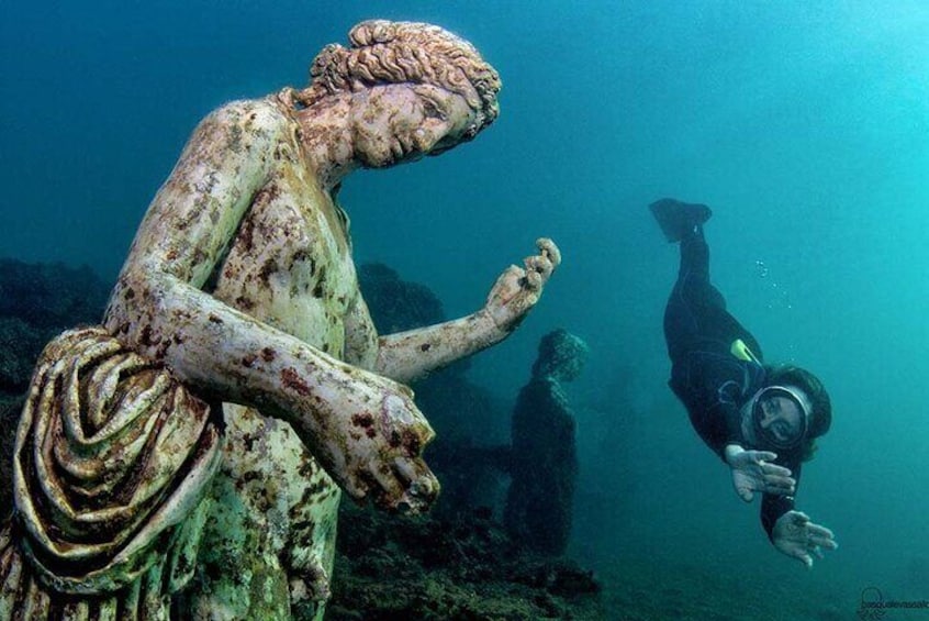 Snorkeler who goes freediving to admire up close one of the statues of the Nymphaeum of Claudius