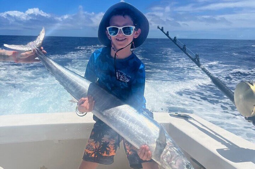 This little angler holding up a caught Ono (Wahoo).