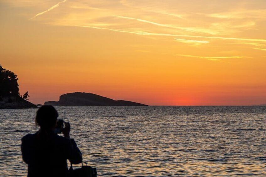 High-contrast sunset in Cavtat with a person in the foreground capturing the moment.