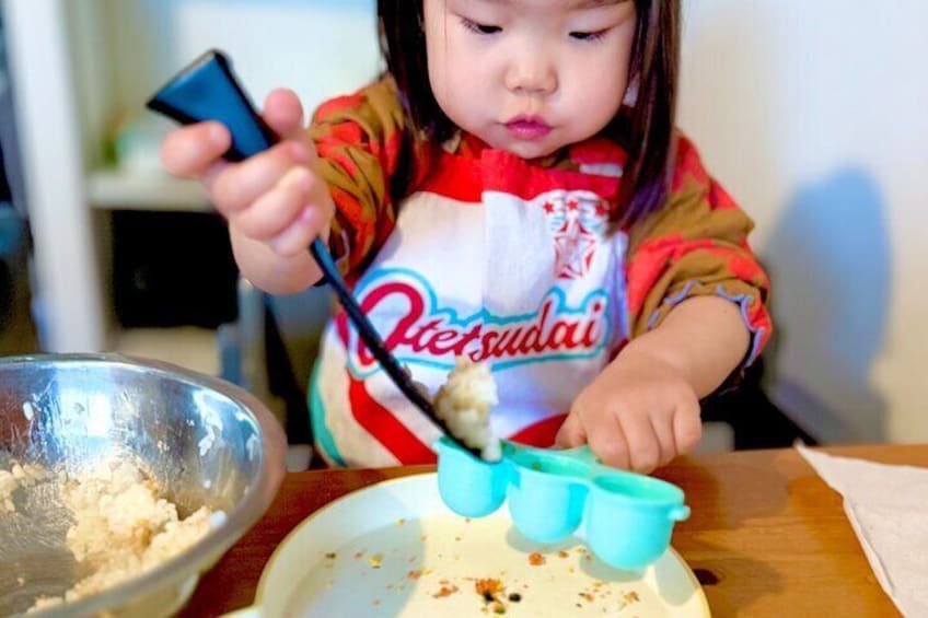 Having fun making rice balls—an adorable hands-on cooking moment for our little chef!