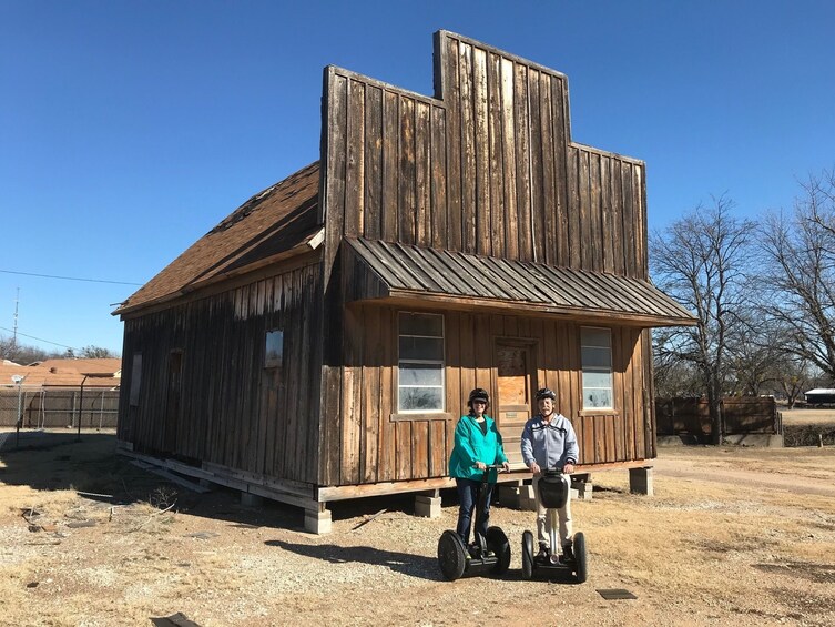 Segway riding couple outside wooden building in Granbury, Texas