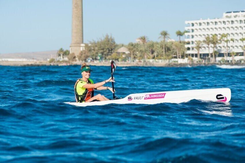 A paddler on surfski sailing in front of the Maspalomas Lighthouse in Gran Canaria
