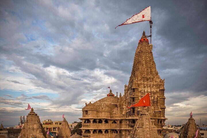 “Bathed in the golden hush of twilight, the Dwarka Temple rises like a hymn carved in stone—its fluttering flags whispering centuries of devotion, its spires reaching not just to the sky, but into the