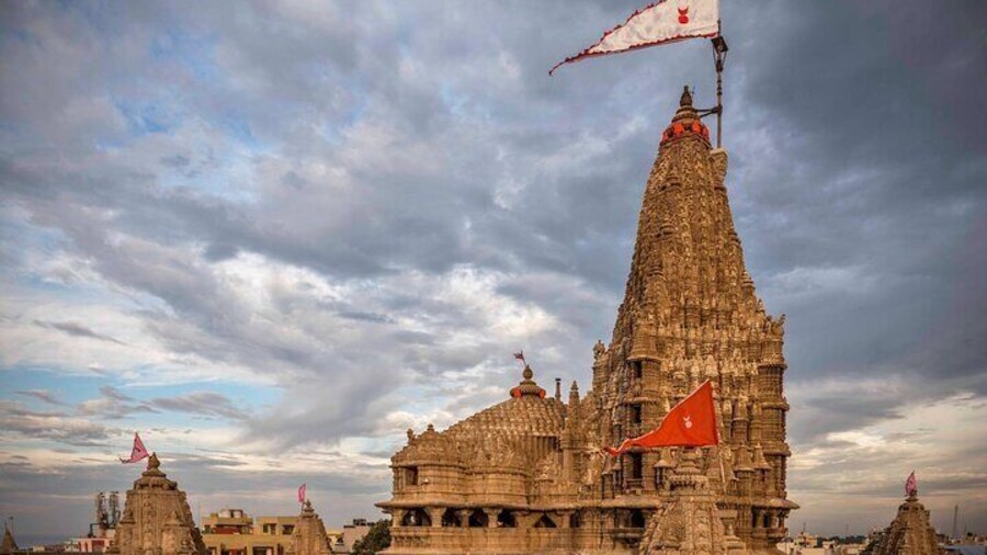 “Bathed in the golden hush of twilight, the Dwarka Temple rises like a hymn carved in stone—its fluttering flags whispering centuries of devotion, its spires reaching not just to the sky, but into the