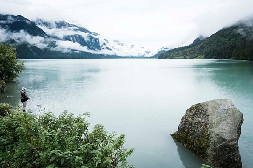 A fisherman stands in the calm waters of Chilkoot lake on a misty morning.