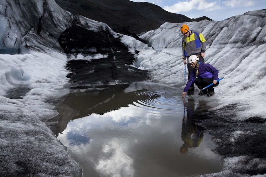 Man and woman stand by water with ice picks in Iceland
