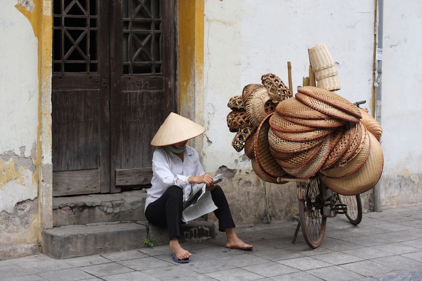 Woman with bicycle loaded up with baskets on the street in Hanoi