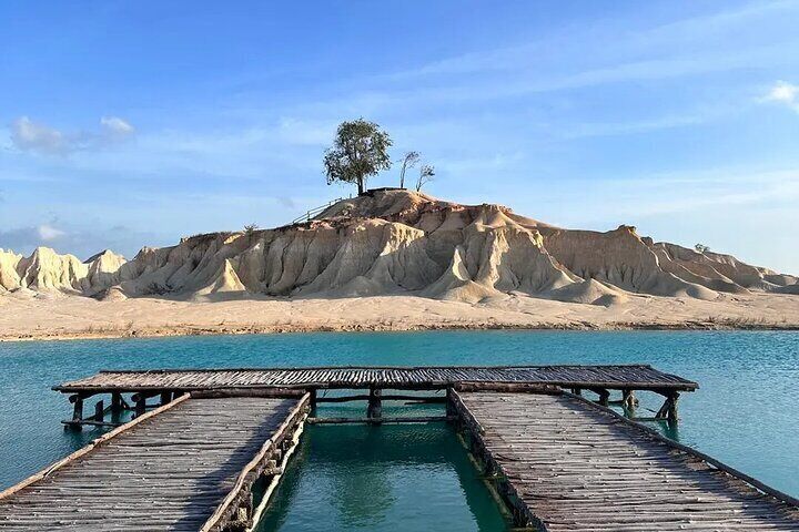 Bright turquoise lake surrounded by white sand hills.