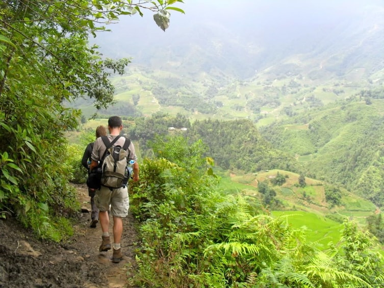 Hikers hike on trail through foggy Sapa Valley