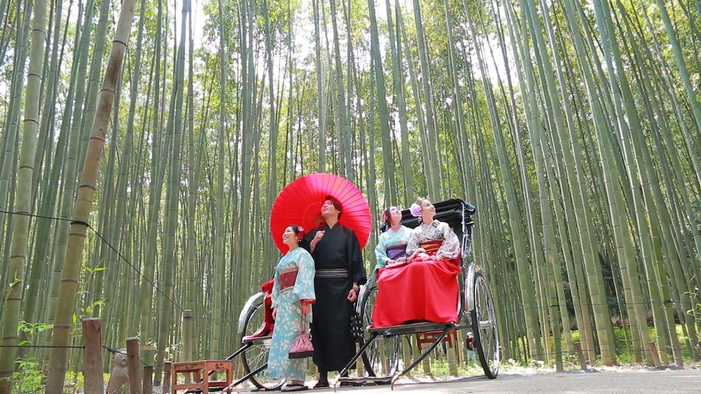 Group in traditional Japanese clothes on a rickshaw carriage ride through bamboo forest