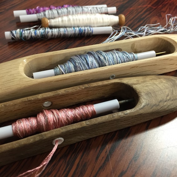 Spools of grey and pink silk thread in wooden holders