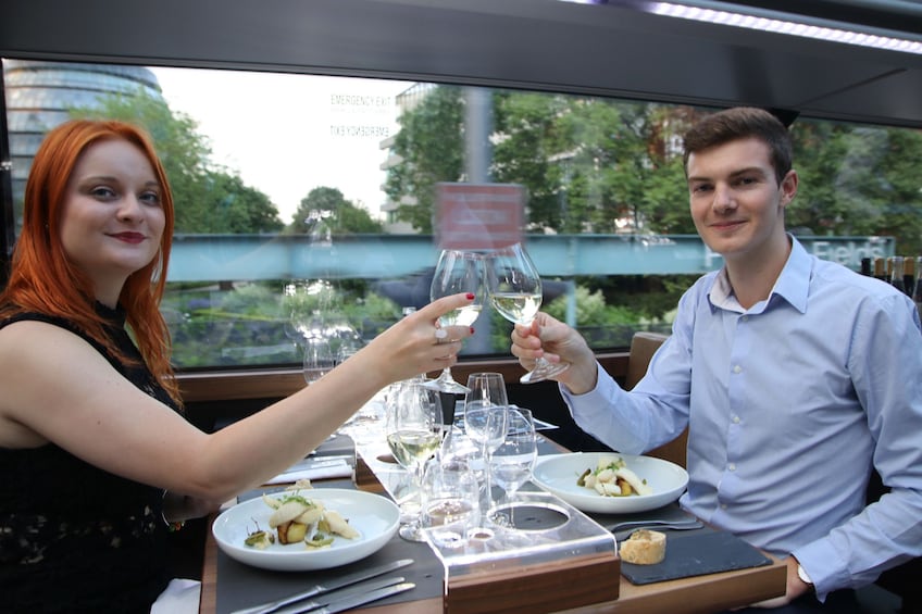 Charger l’élément 5 sur 10. Couple enjoying drinks aboard the BUSTRONOME double decker bus in London