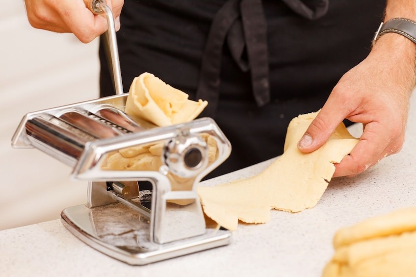 Person rolling pasta through pasta machine