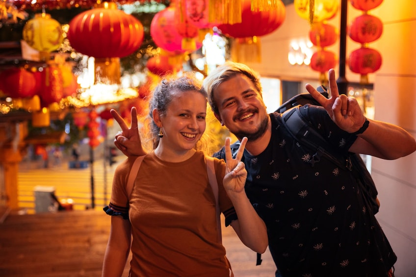 Couple under paper lanterns strewn over the street at night in Hong Kong