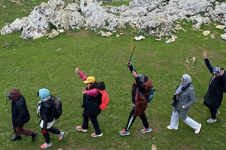 Hikers exploring the White Mountain hiking Tetouan area, walking through green meadows surrounded by rocky peaks