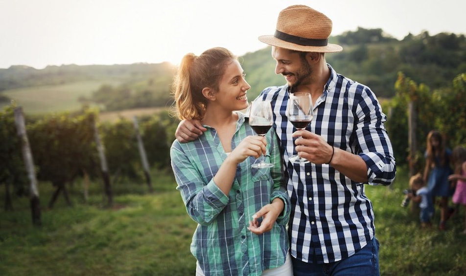 Couple enjoying red wine while walking about a Chianti vineyards 