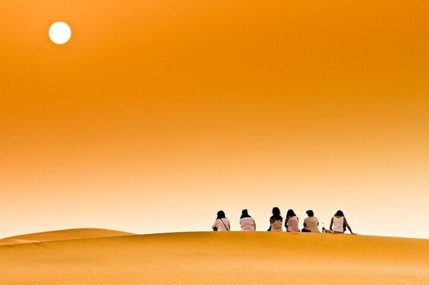 Tourists on dune II comtemplating sunrise in Merzouga - Morocco.