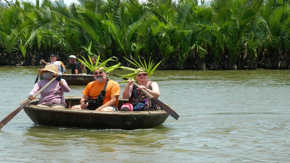 Tourists and guide row basket boat on Thu Bon River in Vietnam