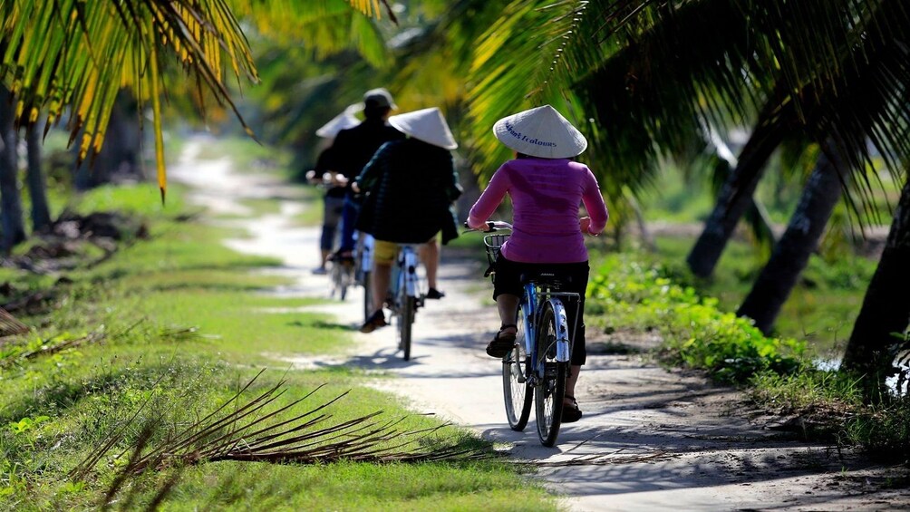 Tourists ride bikes through lush Tra Nhieu Fishing Village