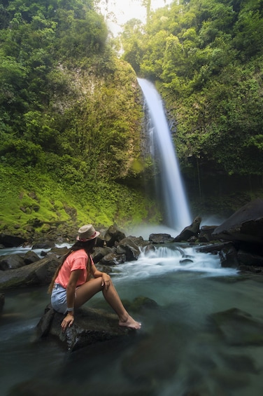 Woman sitting on a rock near a waterfall in Costa Rica