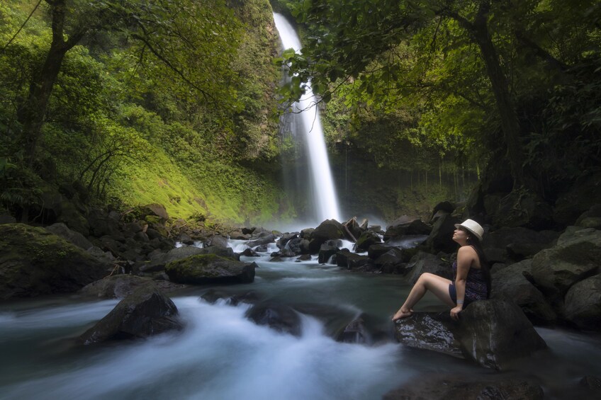 Woman sitting by a waterfall in Costa Rica