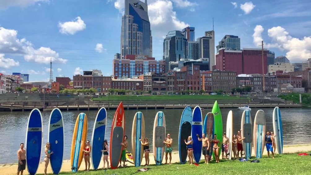 Group of people standing with paddle boards next to a river in Nashville
