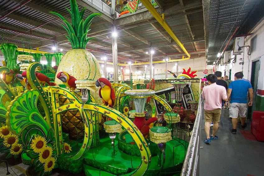 Tourists walk by bright green and yellow Carnaval float 