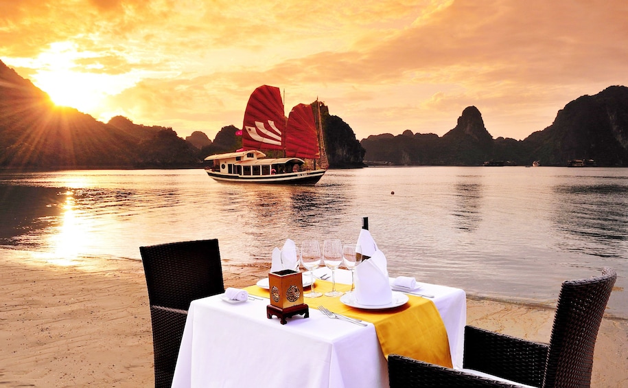 Dinner table on beach on Halong Bay at sunset