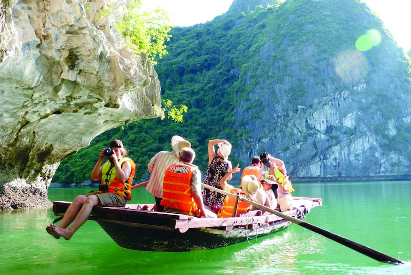 Tourists sit on small boat in Halong Bay