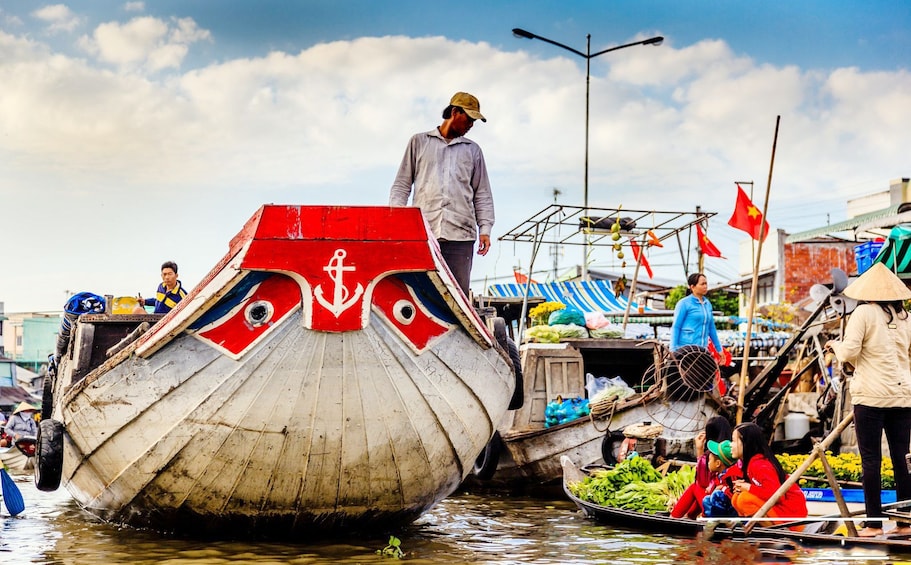 Man stands on fishing vessel next to street market