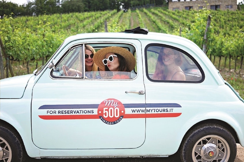Group of people in a 500 Vintage next to a vineyard