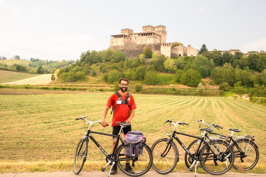 Show item 1 of 6. Man stands with 3 bikes in front of a castle in Parma