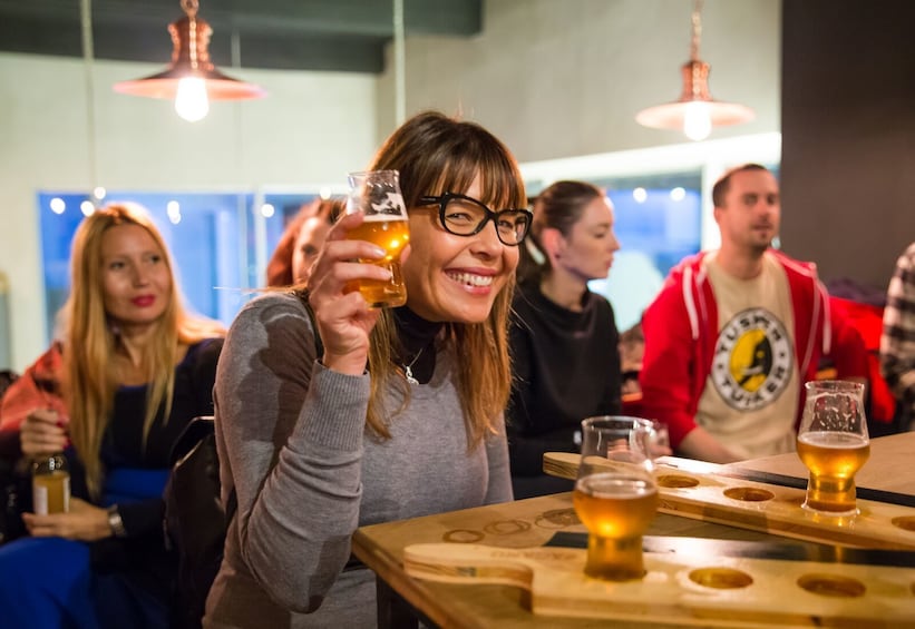 Woman holding up a cup of beer in Bucharest