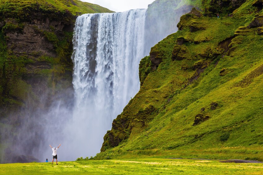 Waterfall next to green hillsides in Iceland