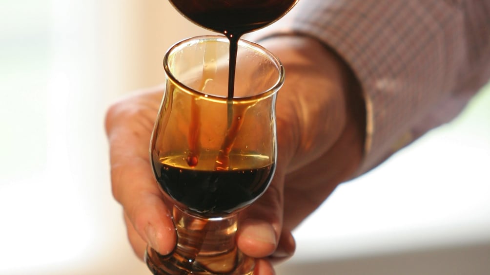 Man pouring balsamic vinegar into a glass on a tour in Modena