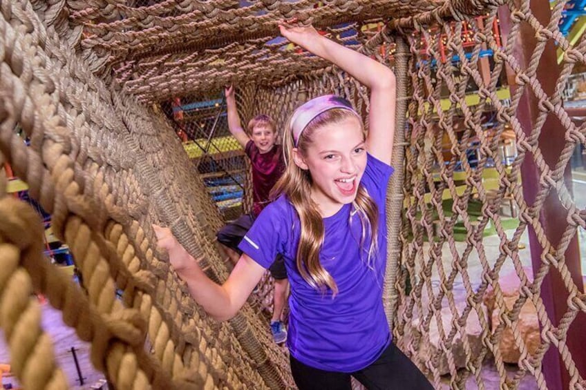 Connected by rope bridges, three vertical climbing treehouses varying in size.