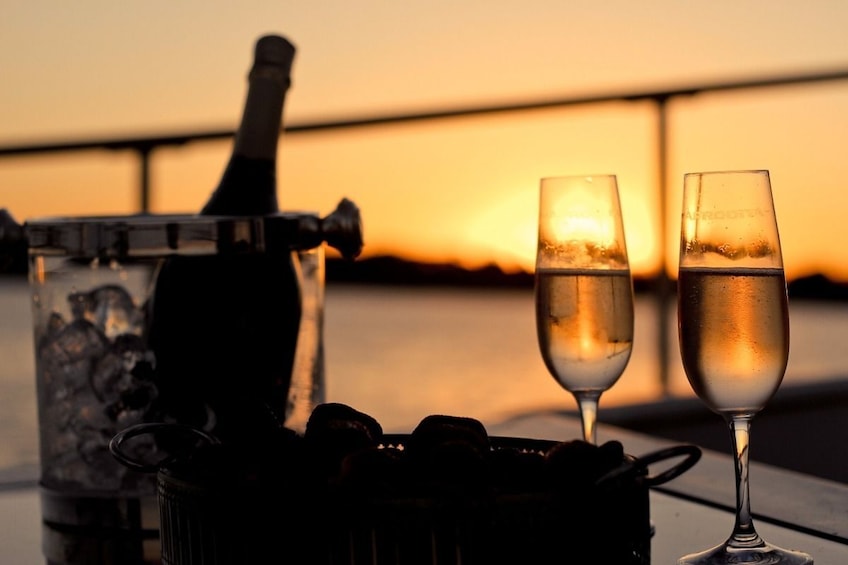 Show item 3 of 9. Glasses of champagne at sunset on a dinner cruise in Cagliari