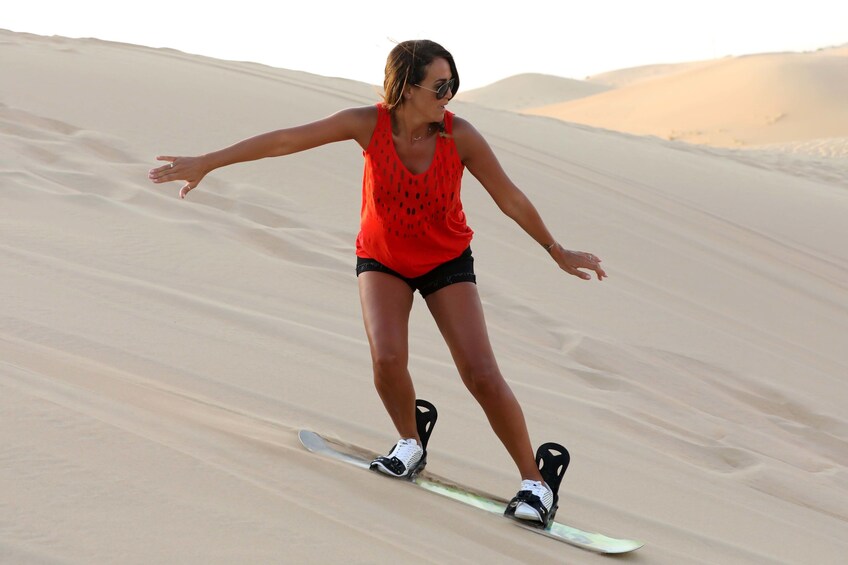 Woman sandboarding in Khatim Desert