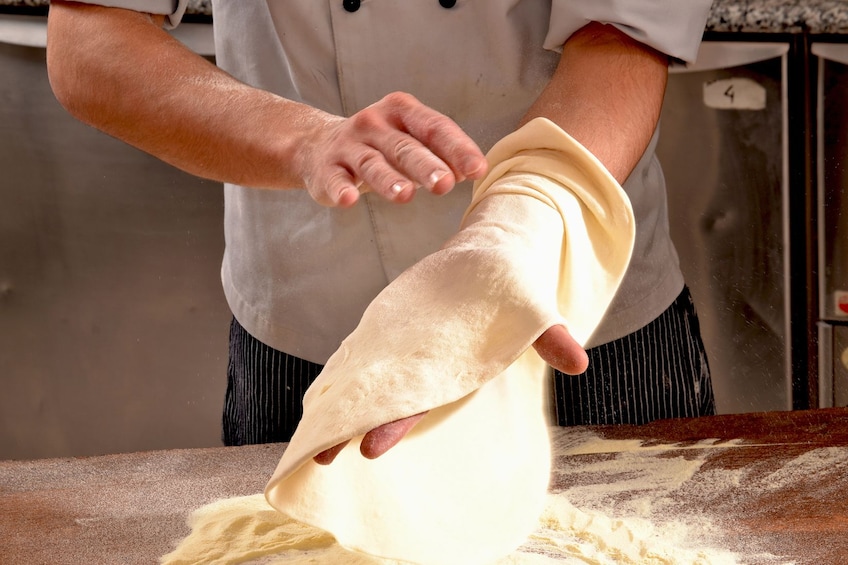 Medium shot of man creating pizza dough