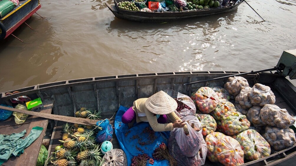 Woman selling pineapples amongst other fruit at the Cai Be floating market 