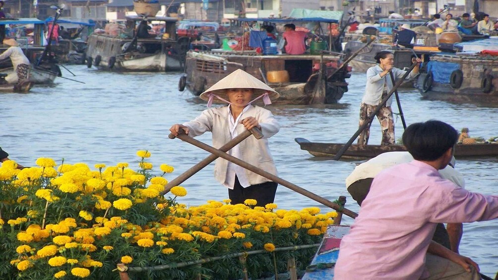Woman transporting fresh flowers at the Cai Be Floating Market 