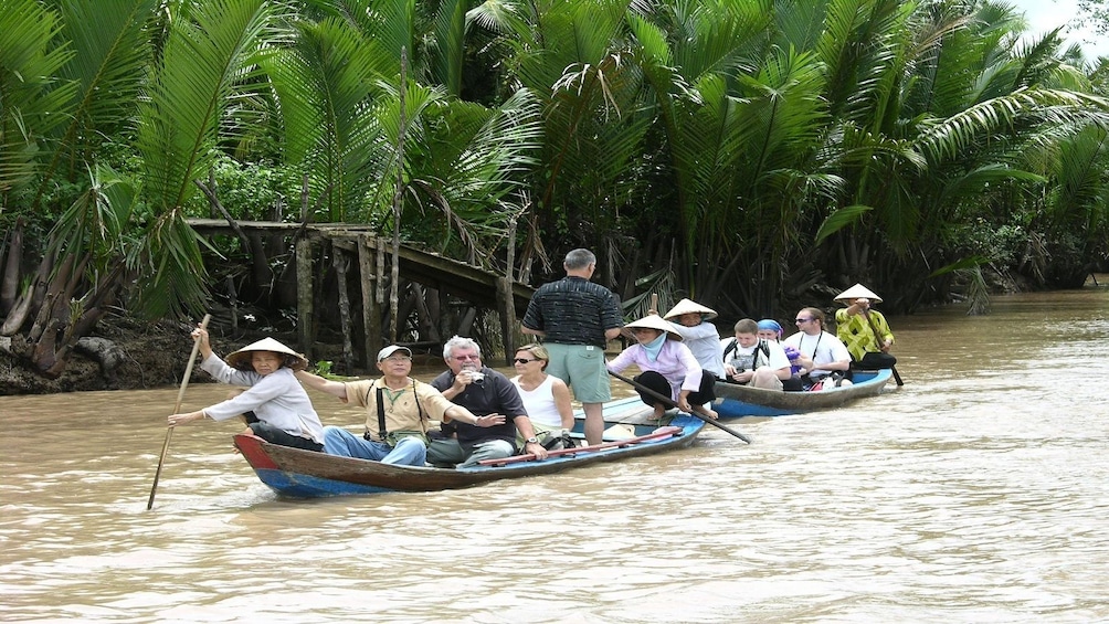 Tourists floating down the Mekong Delta by wooden boat in Vietnam