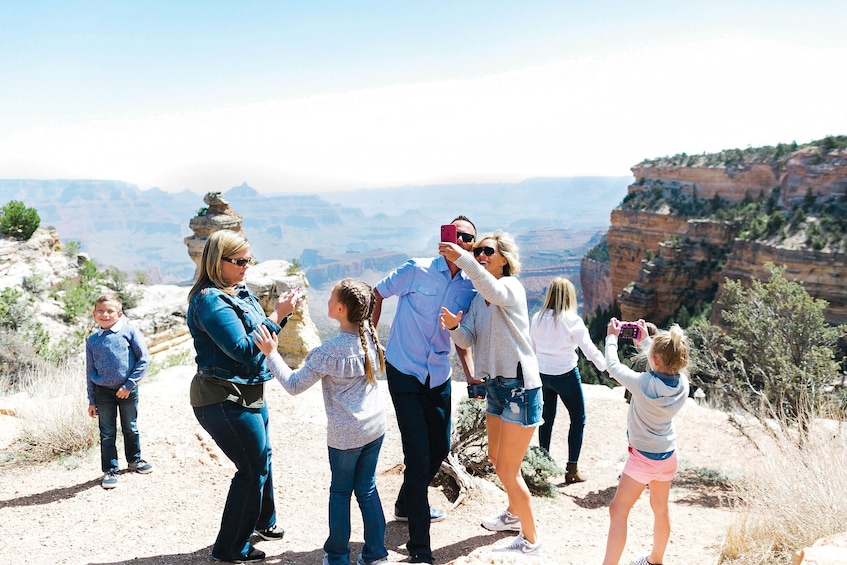Tour group taking photos of the Grand Canyon South Rim via mobile on a sunny day 