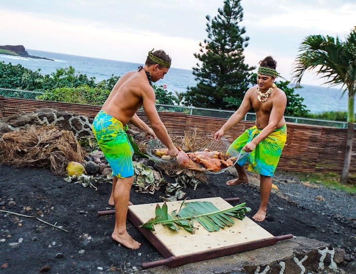 Show item 4 of 10. Two men put a pig underground to roast at a Luau.