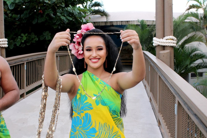 Show item 5 of 10. Woman holds a shell necklace up at a Luau