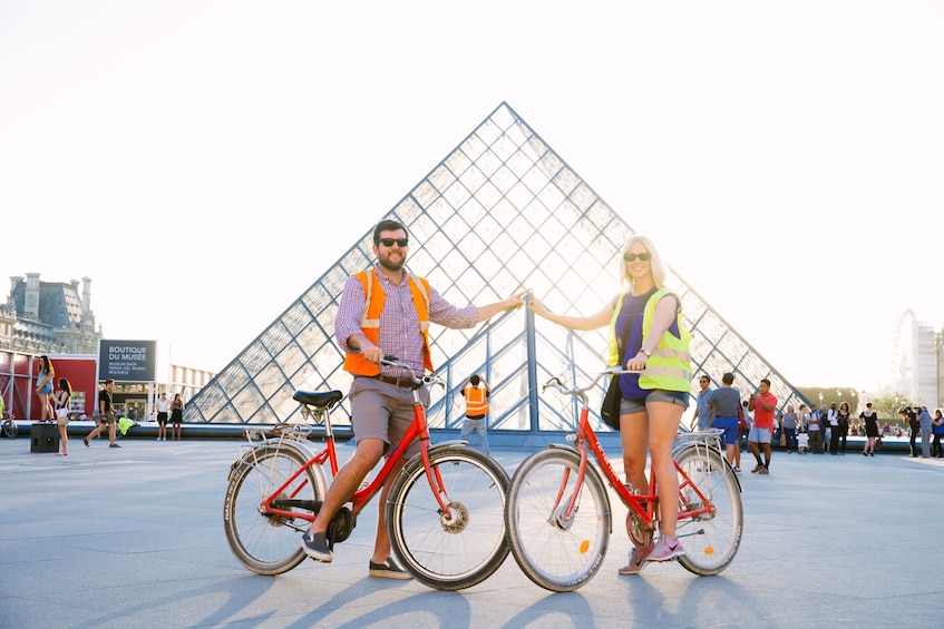 Couple biking in front of the Louvre Museum in Paris 
