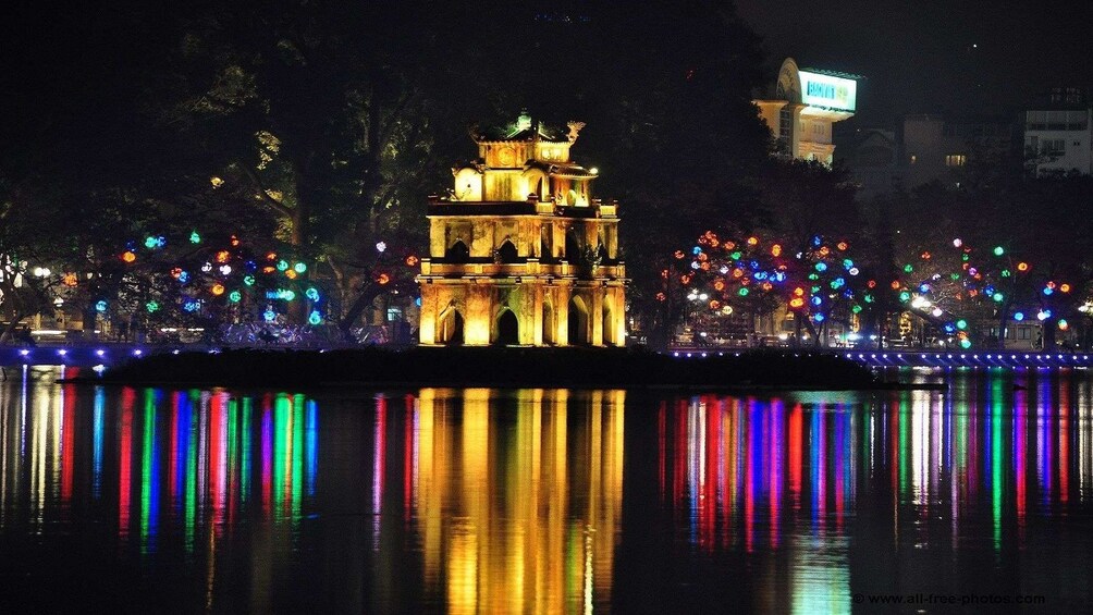 Temple and city lights reflected in a lake in Hanoi