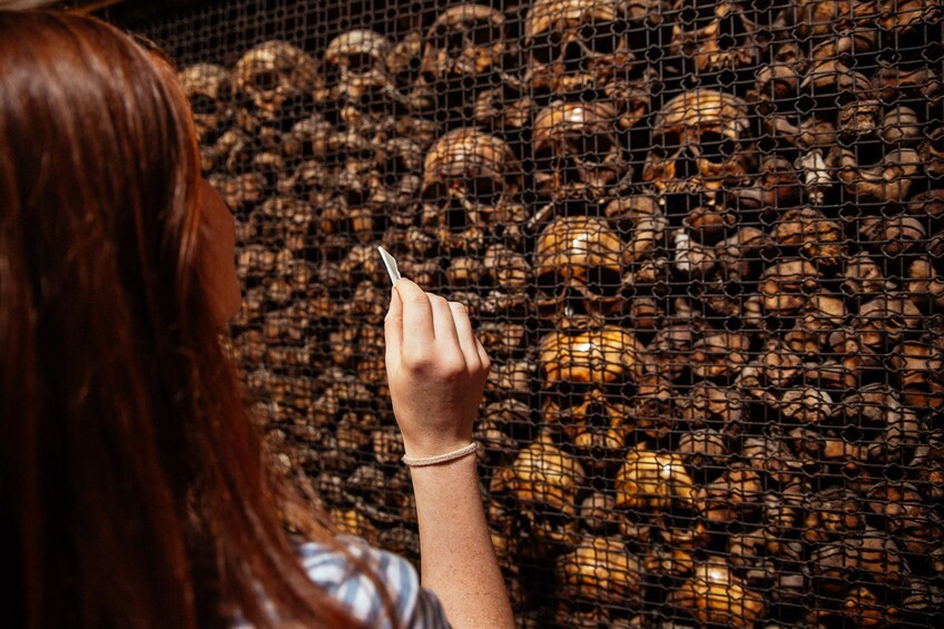 Show item 4 of 8. Woman looking at skeleton heads in Milan