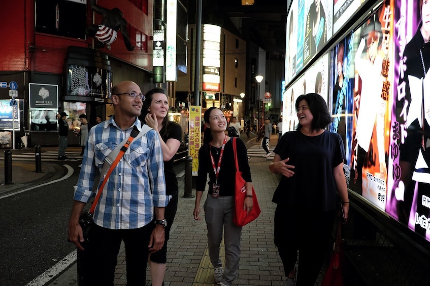 Show item 3 of 8. Group walking along the roads next to the bright billboards in Shinjuku
